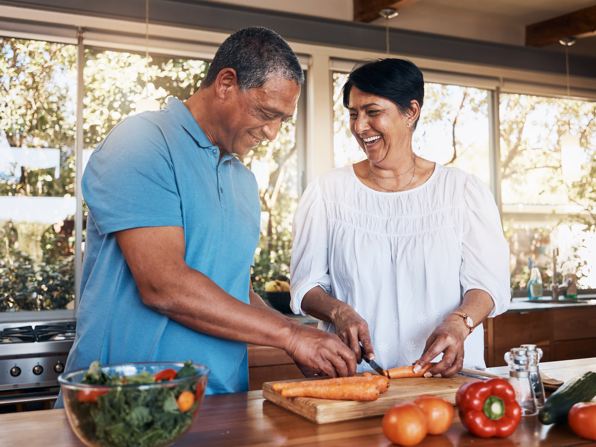 Mature healthy couple cooking in kitchen chopping vegetables for nutritional meal