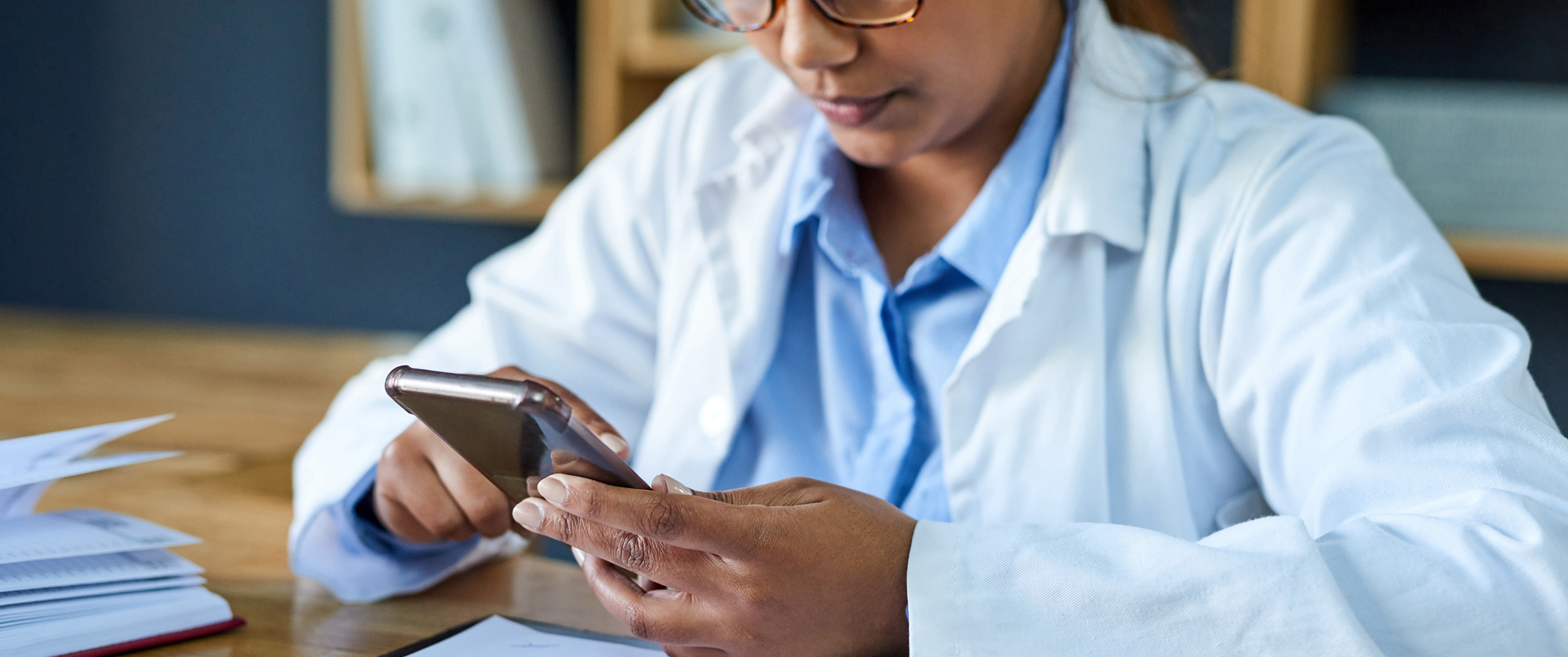 A doctor uses a cellphone while working in an office