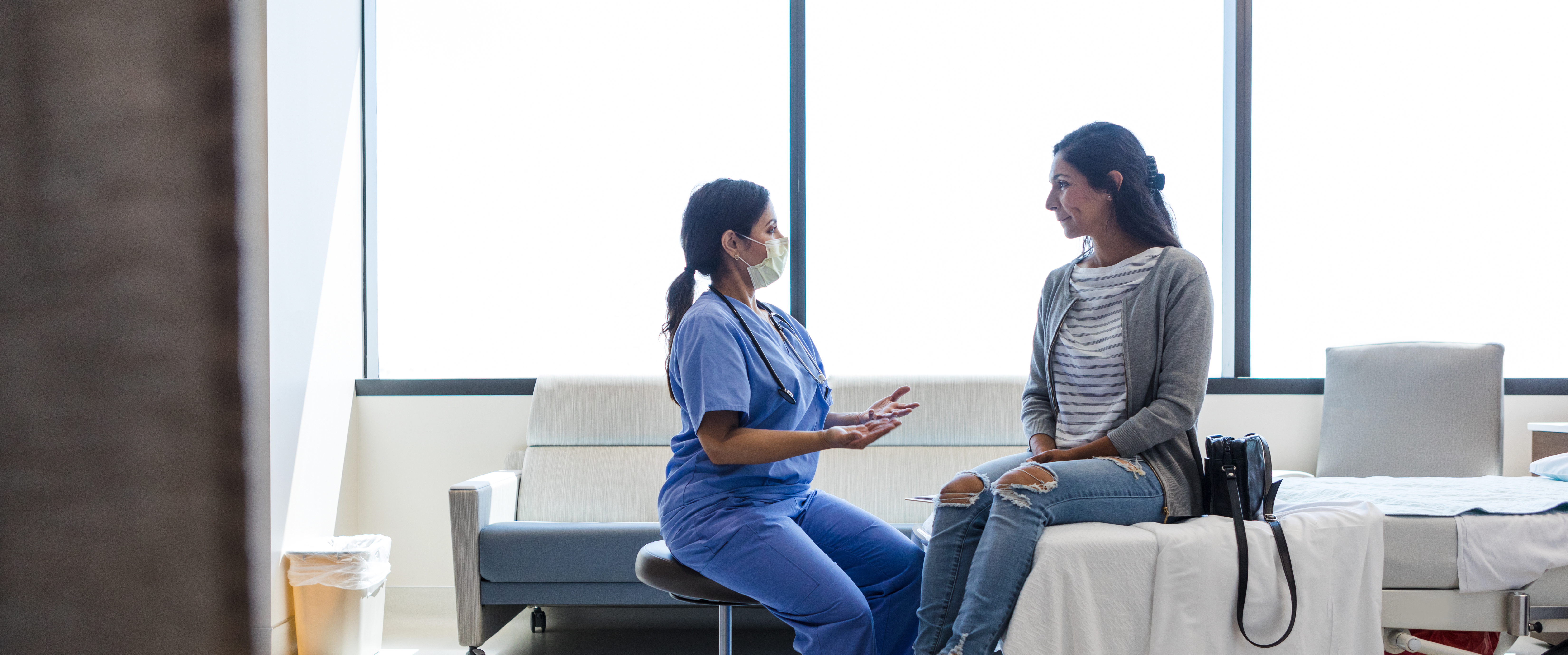 Doctor talks to her female patient in ER examination room