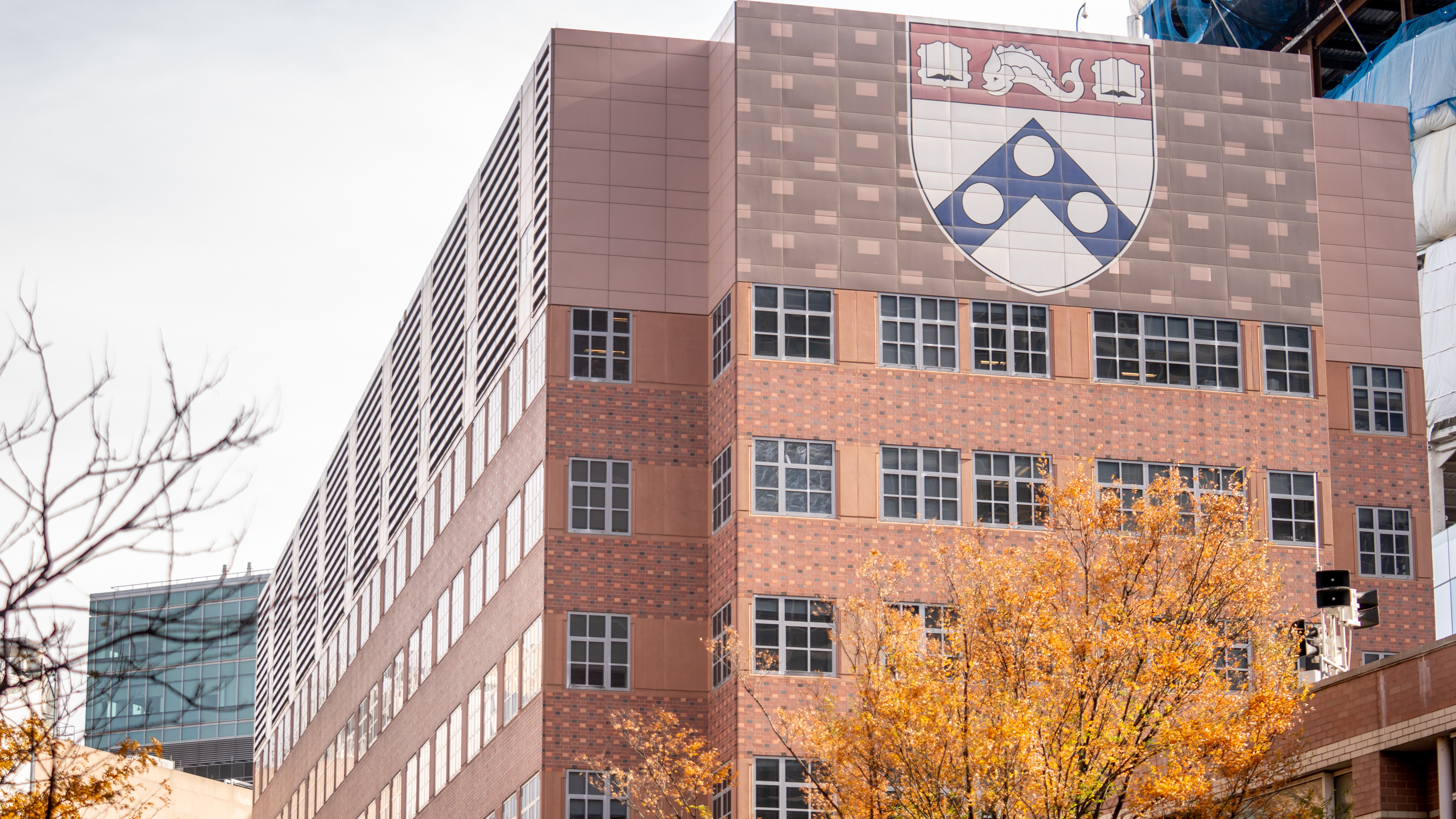 Penn’s Clinical Research Building, a building with multi-color brick patterns on the exterior and a large Penn shield displayed at the top