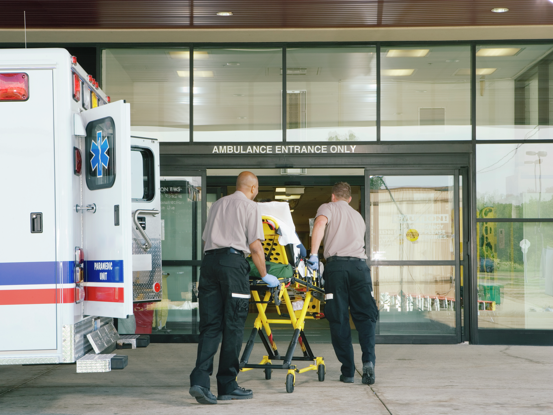 Paramedics taking patient on stretcher from ambulance to hospital