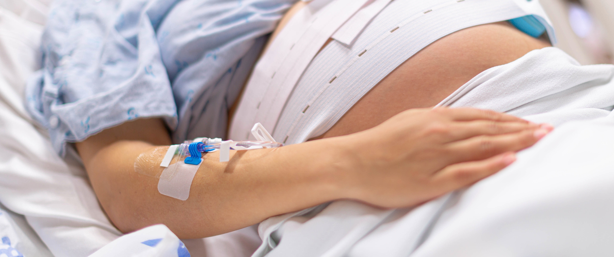 A pregnant woman in the hospital delivery room with a IV drip.