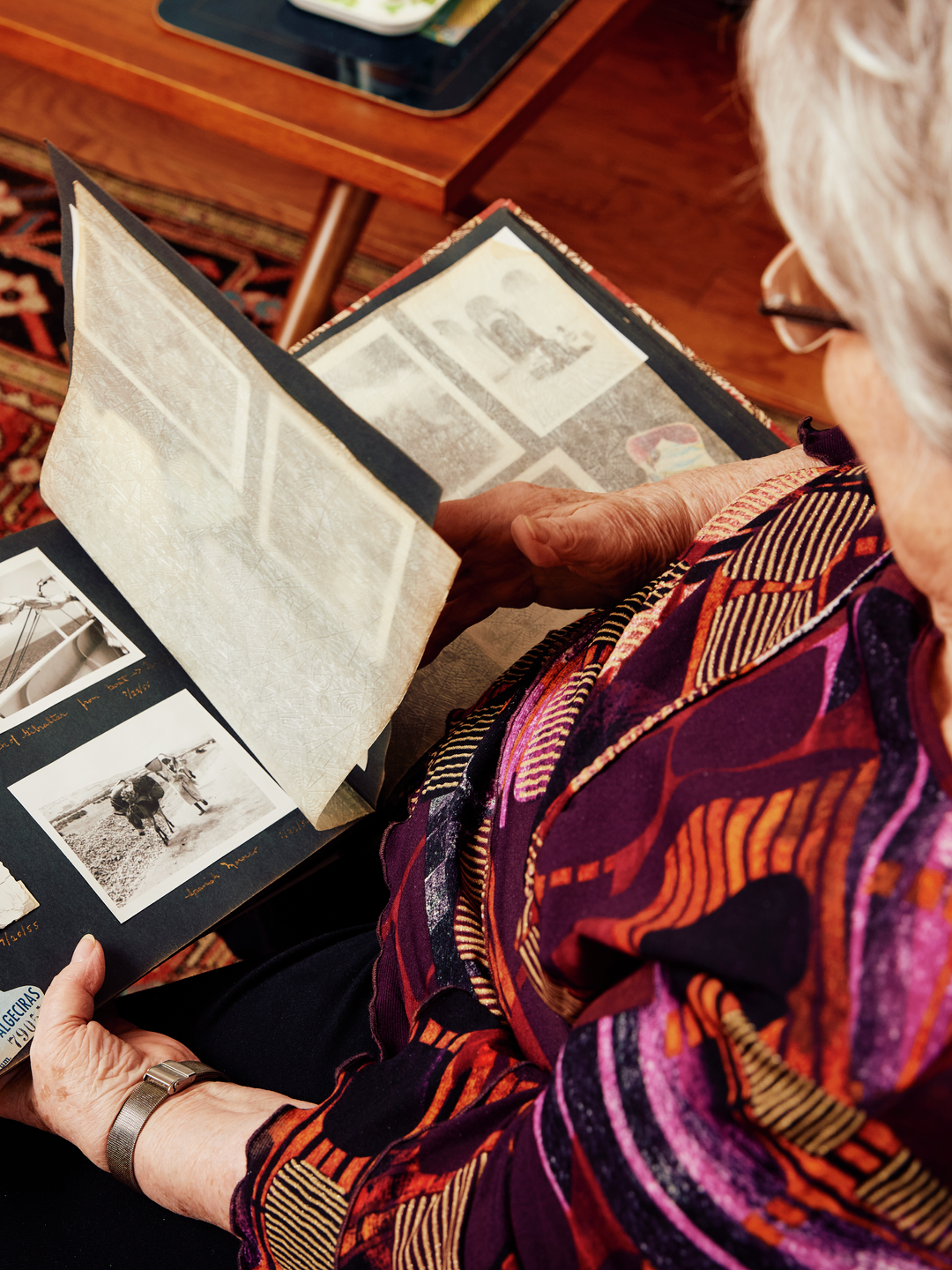 Overhead view of a photo album in Mimi Reed's hands showing black and white photos from the 1950s