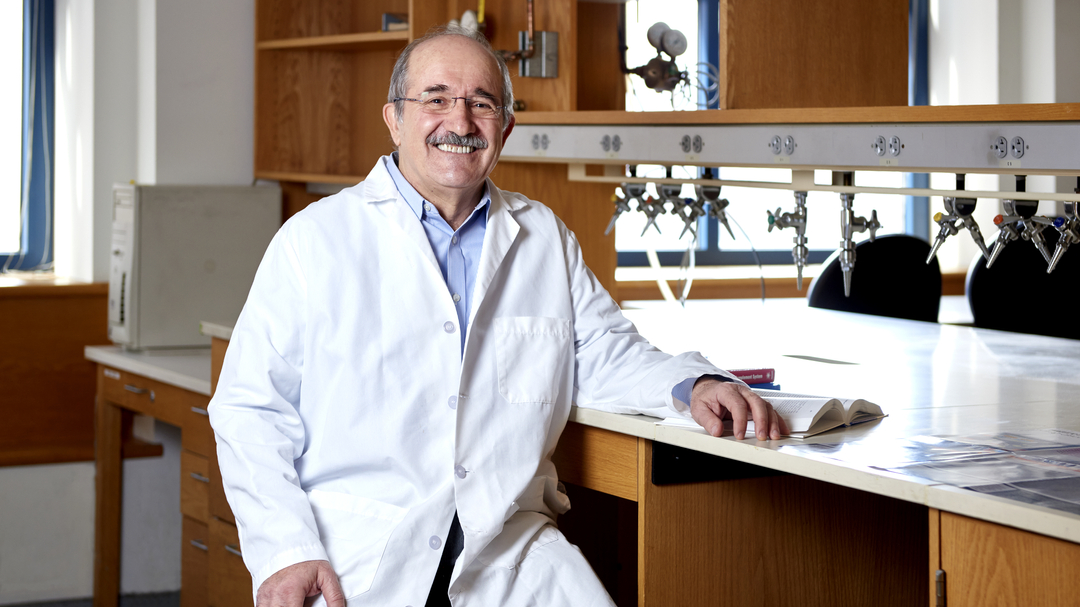 John Lambris sitting at a lab bench, smiling