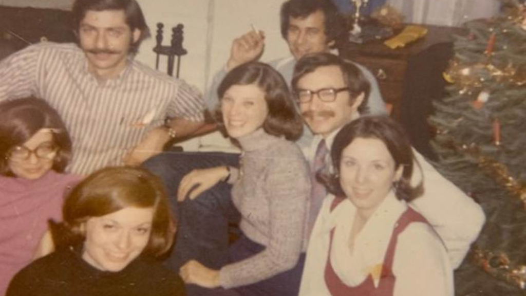 A faded photograph of several young couples in a living room in the 1970s