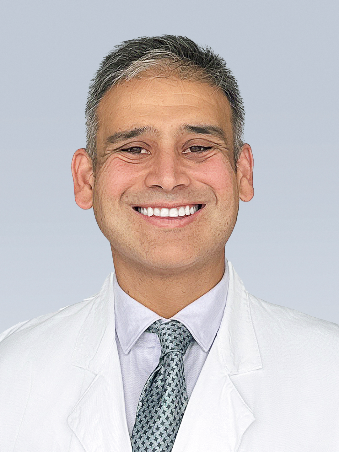 Joshua Stephen Catapano, MD, smiles in a white lab coat, blue dress shirt and silver tie