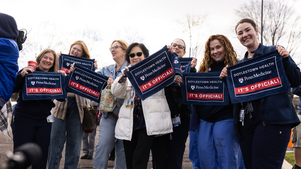 Doylestown Health staff wave rally towels that say "Doylestown Health / Penn Medicine / It's Official!"