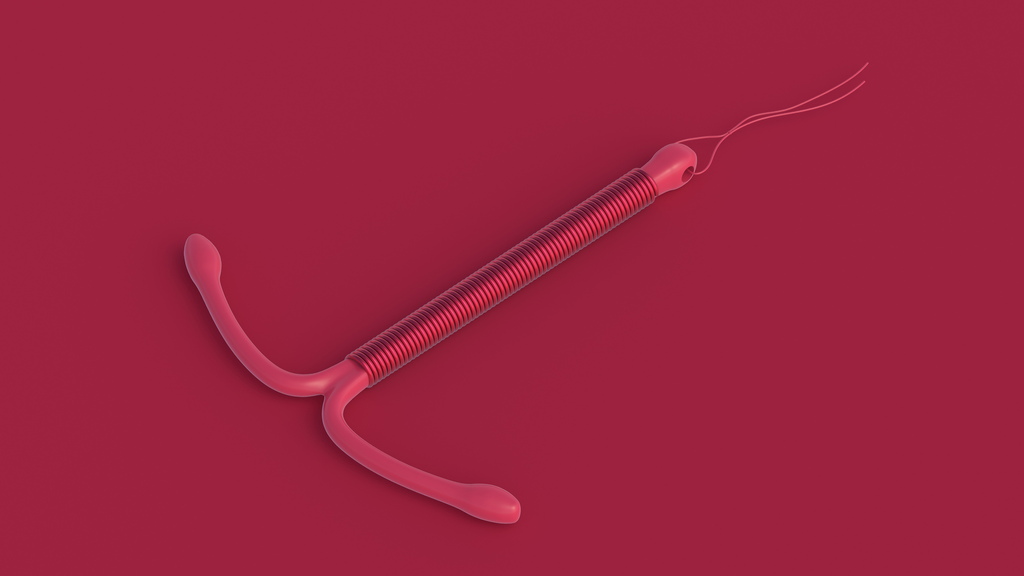 An IUD device laying on a dark red background.