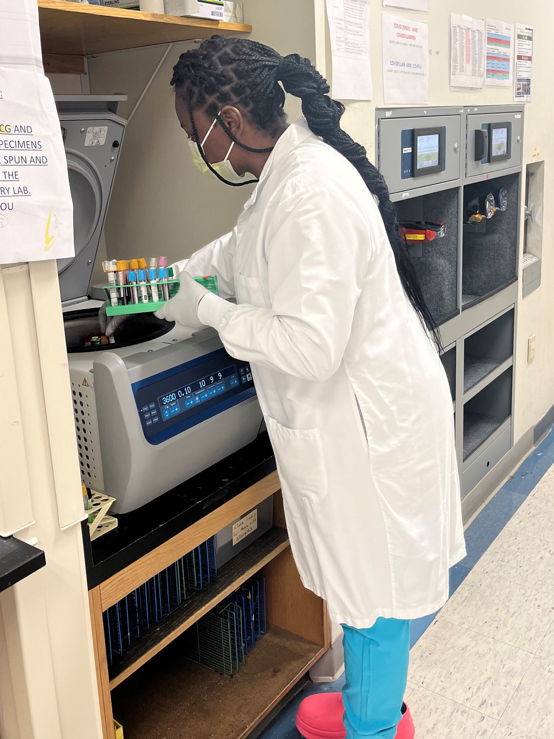 Antoinette Moore, wearing a white lab coat, reaches into a freezer in a pathology lab